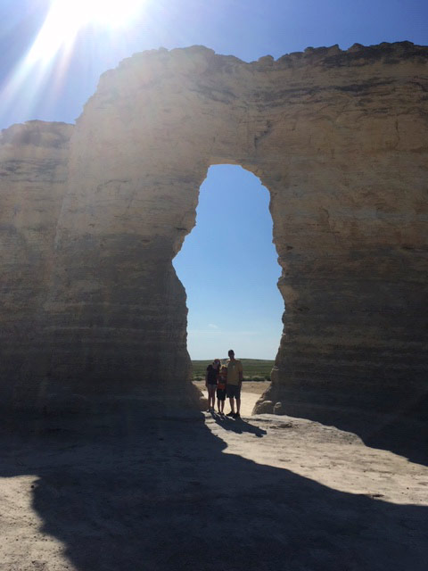 Young family framed by rock arch at Monument Rocks National Natural Landmark