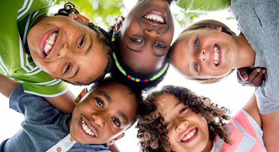 turtle-eye view of happy multicultural kids locking arms