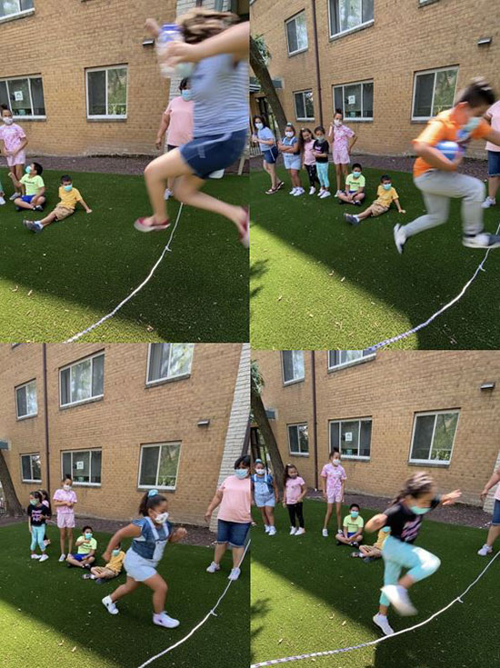 Multicultural elementary-aged kids juming rope outside at summer youth program