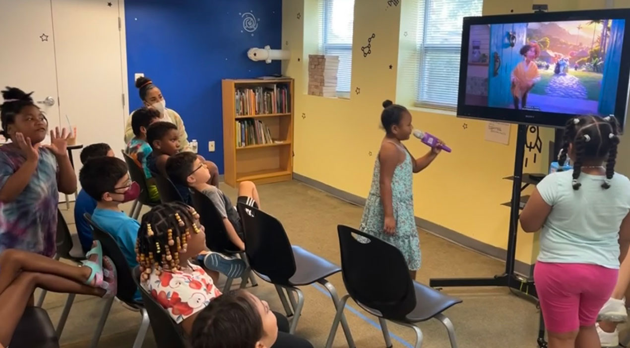 Young girl doing karaoke with a group of kids