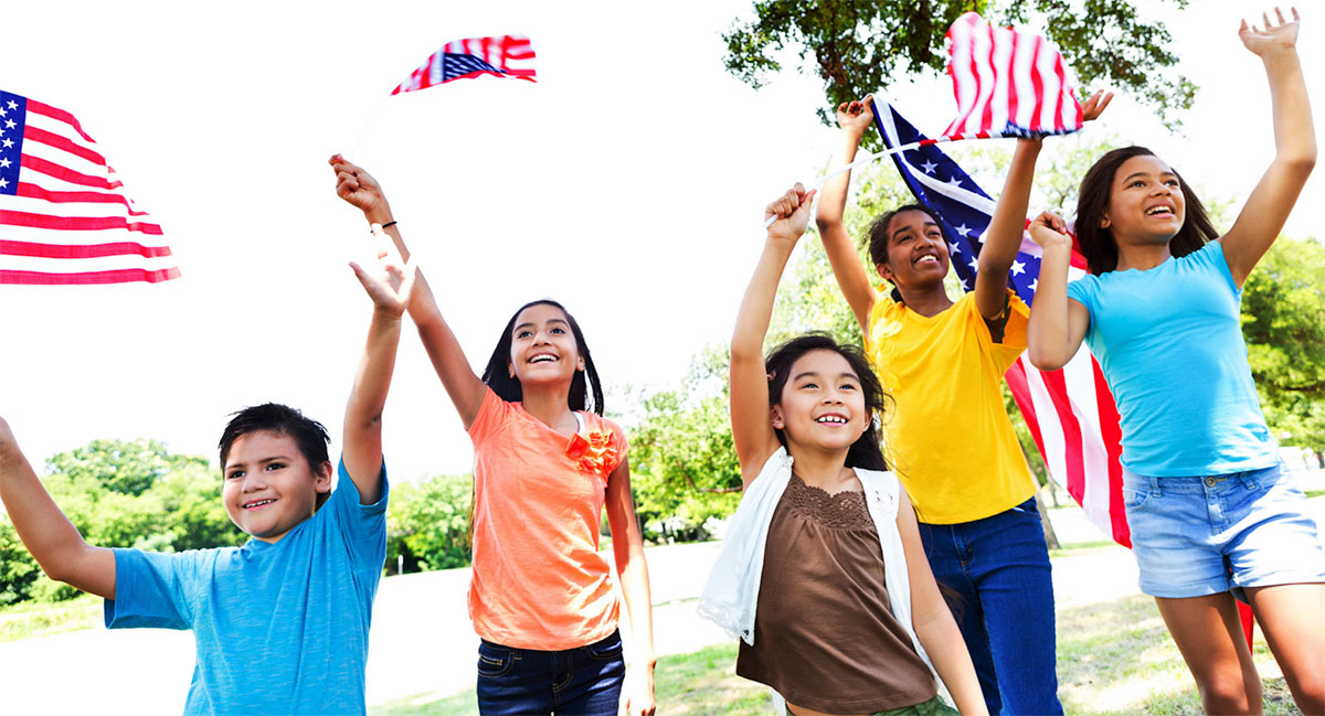 multicultural kids outdoors waving American flags