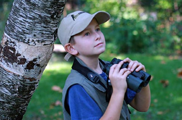 Young boy outside with binoculars
