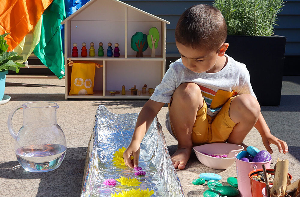 child building a dam with cardboard, foil, and plants