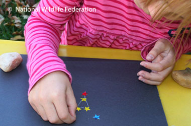 young child making a constellation on black paper