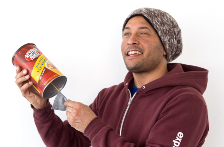 man holding a DIY cuica made from a coffee can