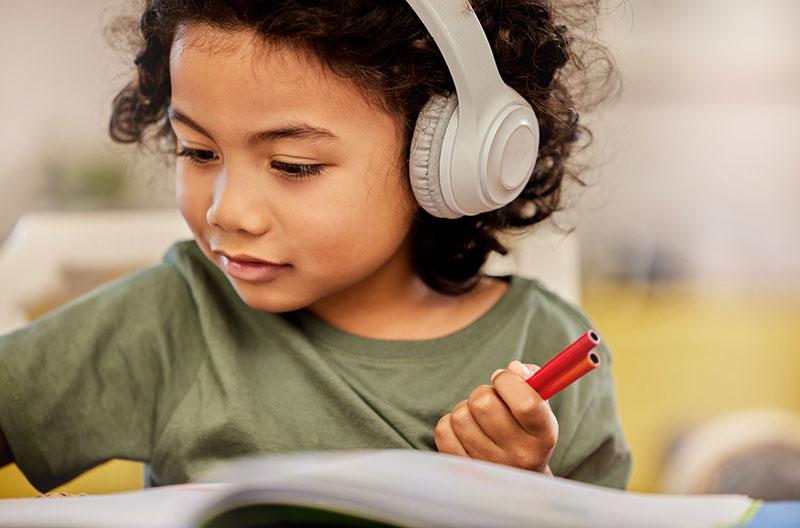 young child drawing while wearing headphones