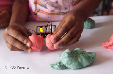 child hooking electrodes to clay balls