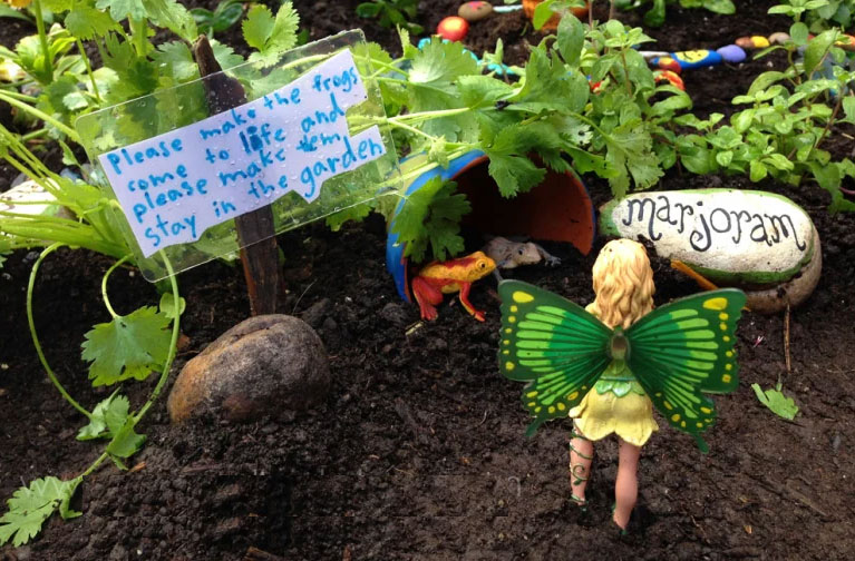 child's backyard fairy garden with fairy figurine