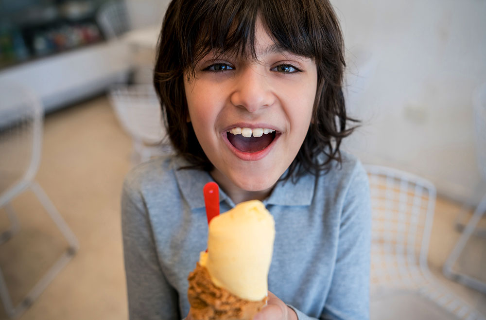 Smiling young child in kitchen with an ice cream cone