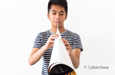 photo of boy blowing through the end of a paper cone