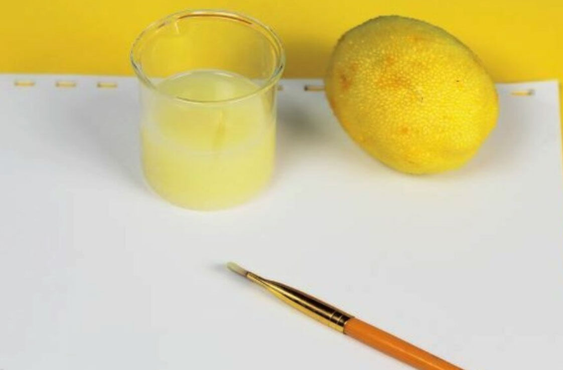 lemon juice, lemon, paint brush and paper
