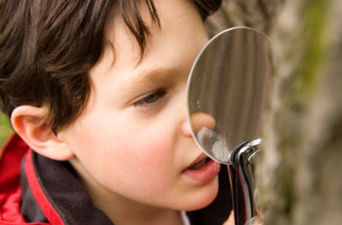 young child looking through a magnifying glass