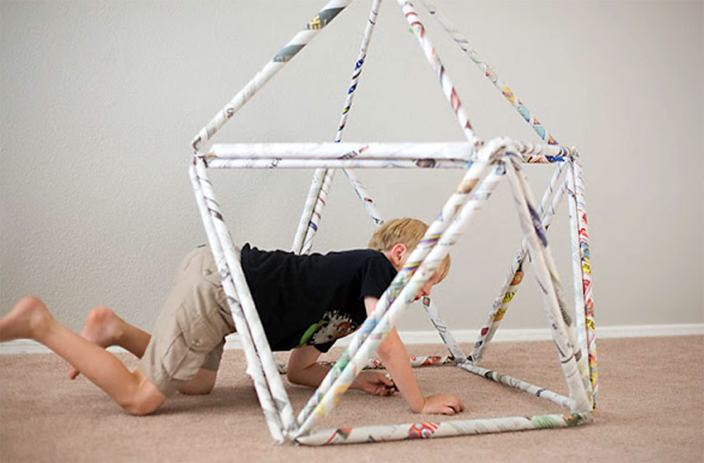 child building a fort out of newspaper