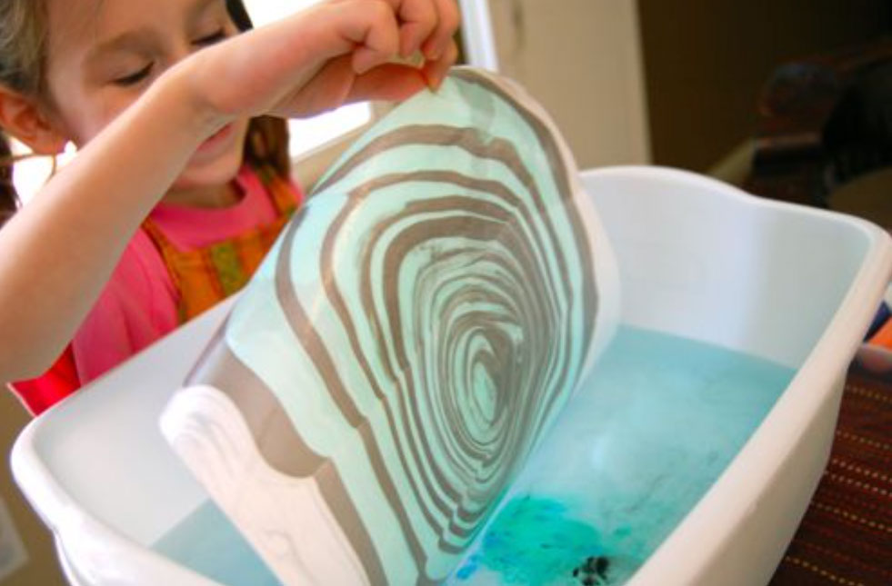 photo of kid holding suminagashi style painting