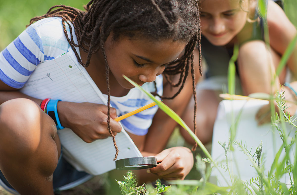 two girls looking at plants outside