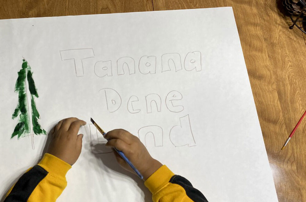child drawing a poster with a tree