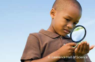 boy looking a something in his palm through a magnifying glass