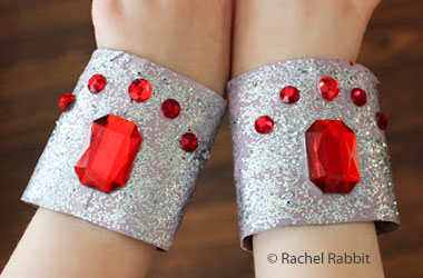 photo of child wearing silver cuffs covered in red stones