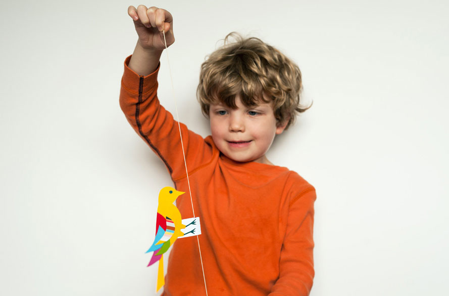 boy holding a paper bird on a string