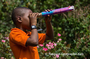 A boy looking through a homemade telescope.