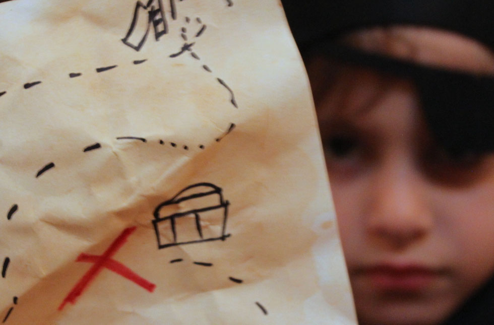 child dressed like a pirate holding up treasure map