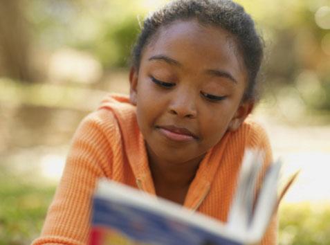 young girl reading a book outside