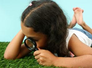 girl looking through magnifying glass at the ground 