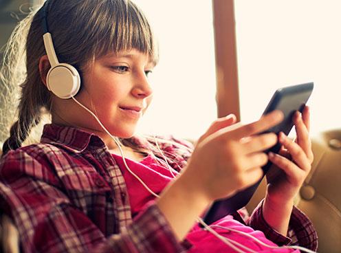 Girl in headphones looking at a smartphone.