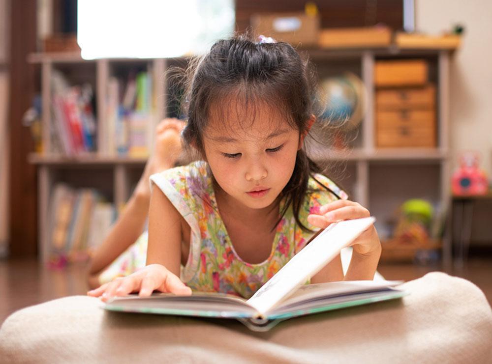 Young girl reading a book in her room