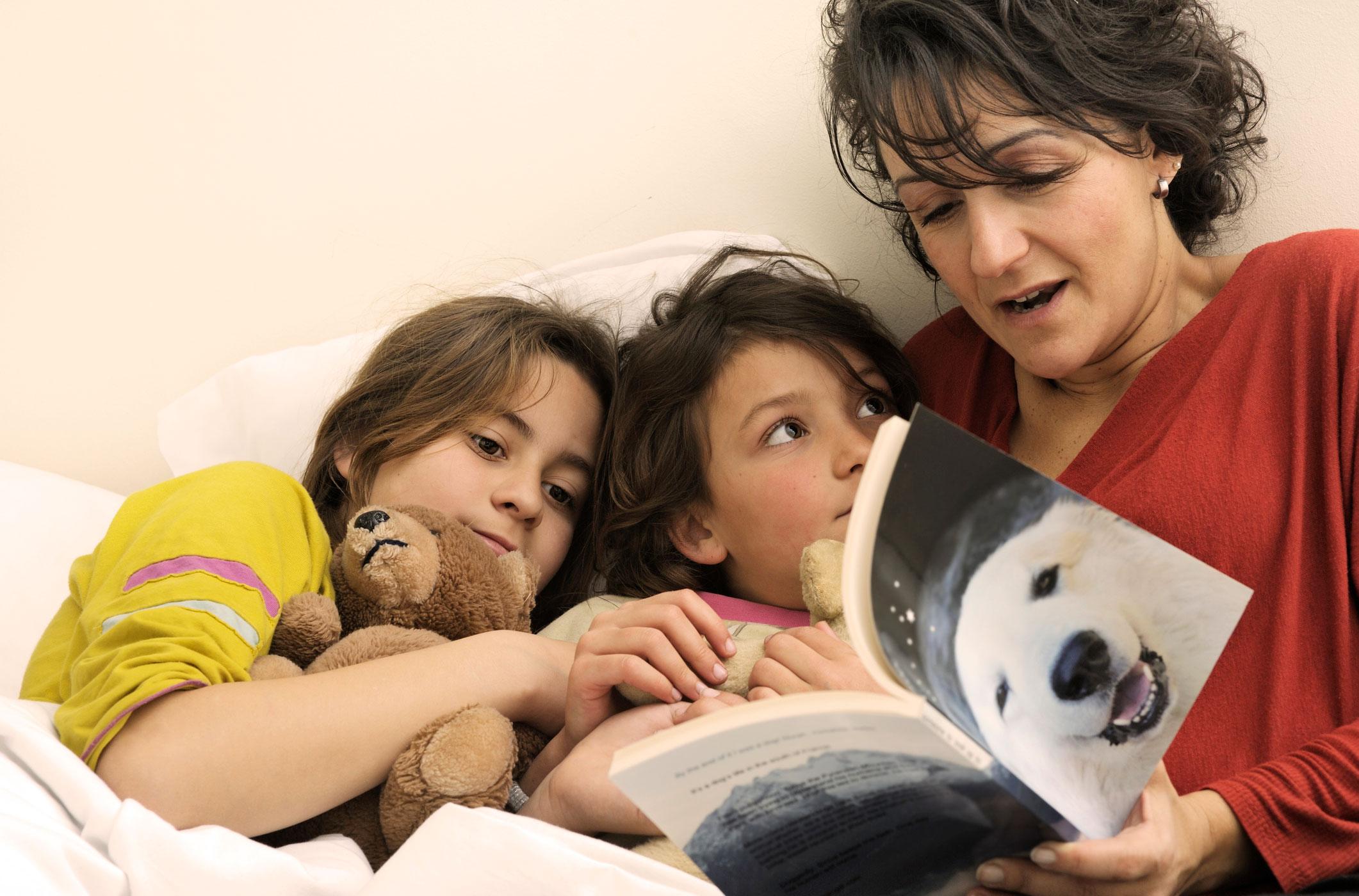 Mother reading books about polar bears to two kids