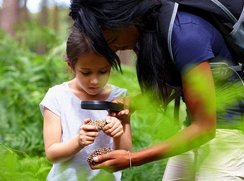 Mother and daughter looking at nature specimen with a magnifying glass outside