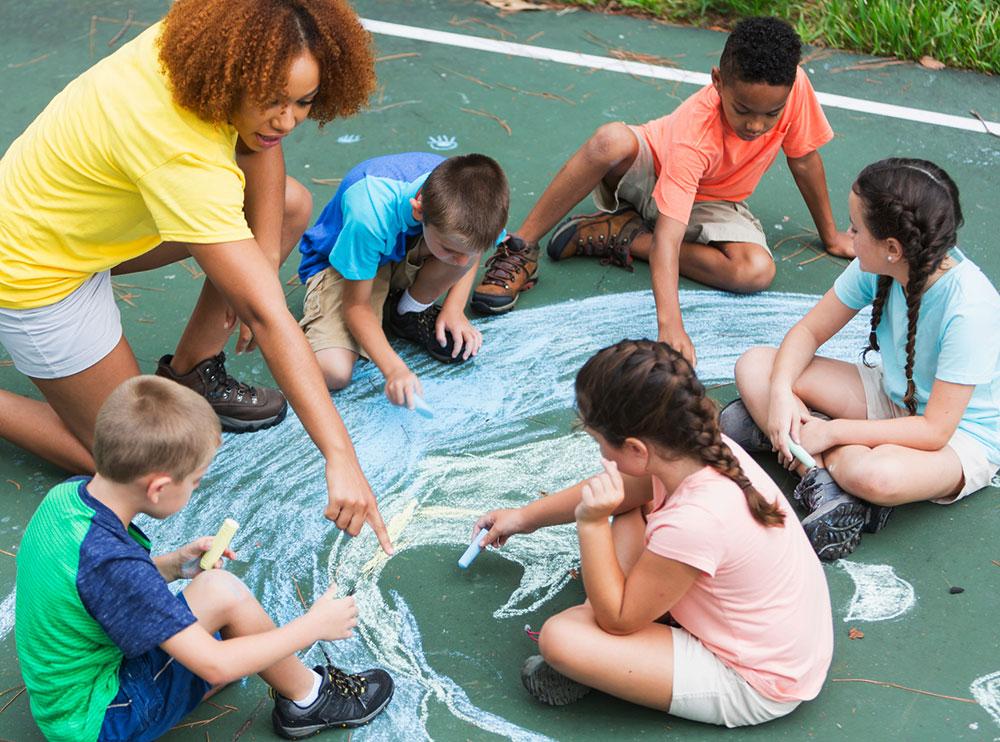 Adult and kids making a chalk drawing of planet Earth