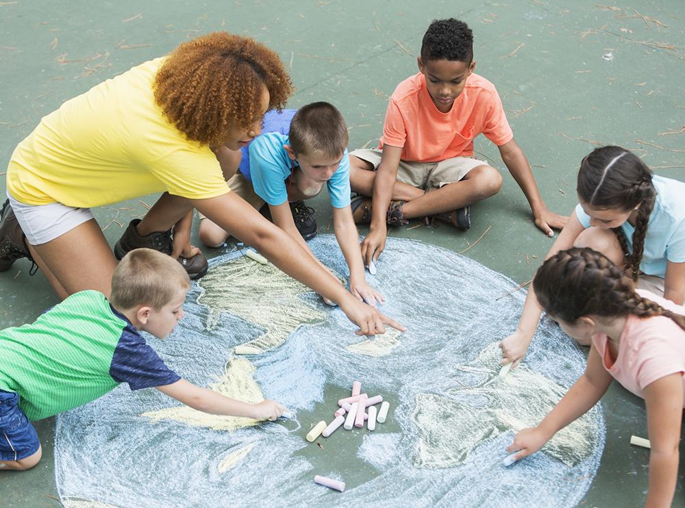Adult and kids making a chalk drawing of planet Earth