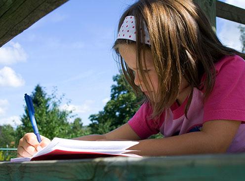 Young girl writing in a journal outside