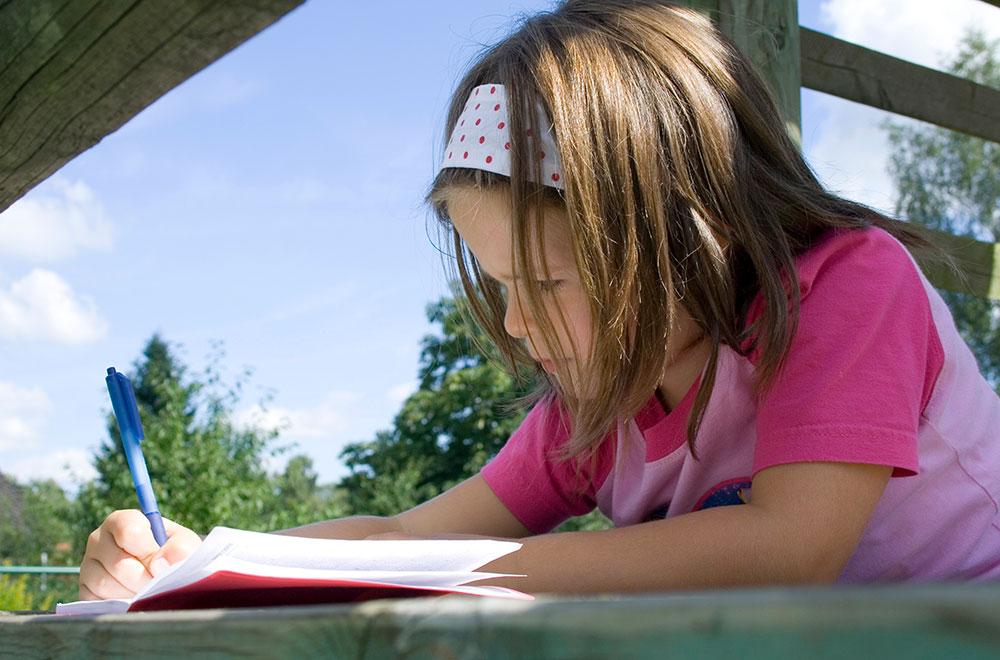 Young girl writing in a journal outside