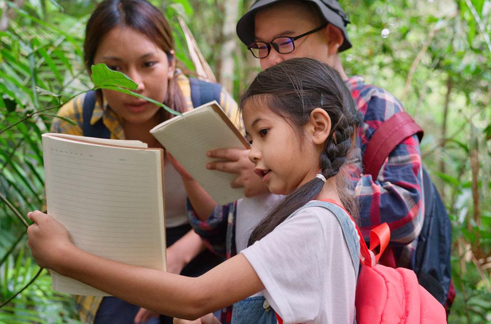 Mother with two kids outside exploring nature and writing in journal