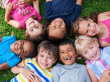 photo of seven children lying on the ground with their heads together in a circle photo of seven children lying on the ground with their heads together in a circle