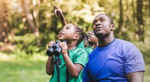 Black father with two young kids birdwatching