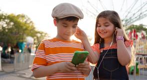 Two kid listening to audiobooks outside on a smart phone