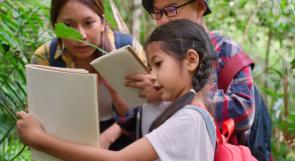 Mother with two young kids exploring nature and writing in journals