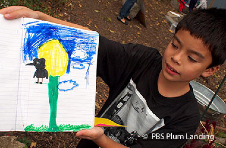 young boy holding up a drawing of a tree, the sky, and a bird