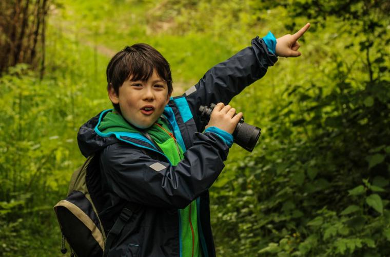 Child using binoculars pointing at bird nest