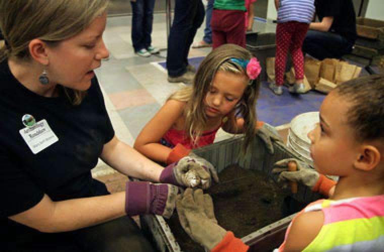 photo of woman helping two kids dig through dirt