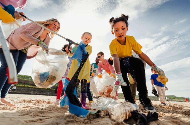 kids cleaning up plastic on the beach