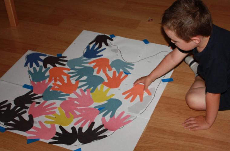 child comparing size of hand with dinosaur footprint