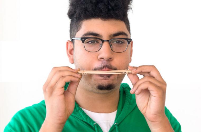 Man blowing on homemade popsicle stick harmonica
