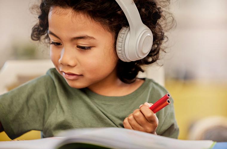 young child drawing while wearing headphones