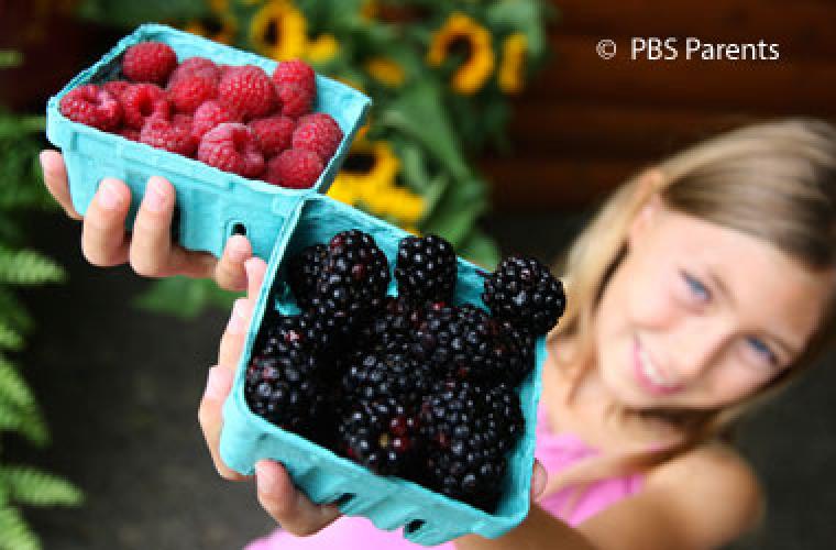 girl holding up containers of berries