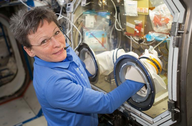 Female astronaut using the glove box on the International Space Station