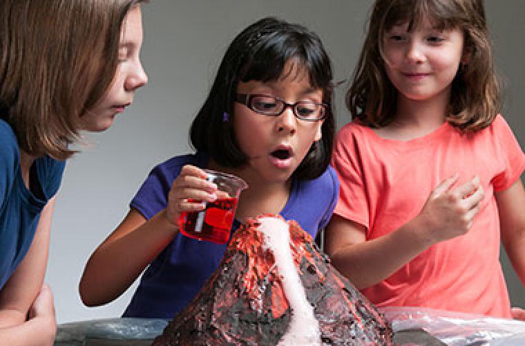 Three kids looking at a homemade volcano.